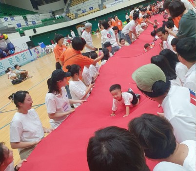 아동보육과-지난해 8월 30일 성남실내체육관에서 열린 제1회 성남시 아장아장 운동회 때 날아라 병아리(긴 천을 부모가 양쪽에서 잡고 아이들이 위로 건너가는 경기).jpg width: 100%; height : 150px